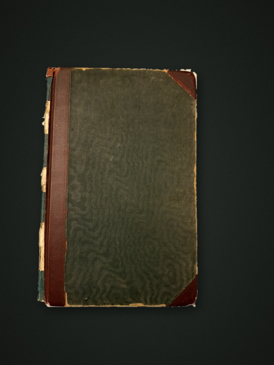 The accounts ledger, closed: green cloth boards with red-brown corners and a worn spine
