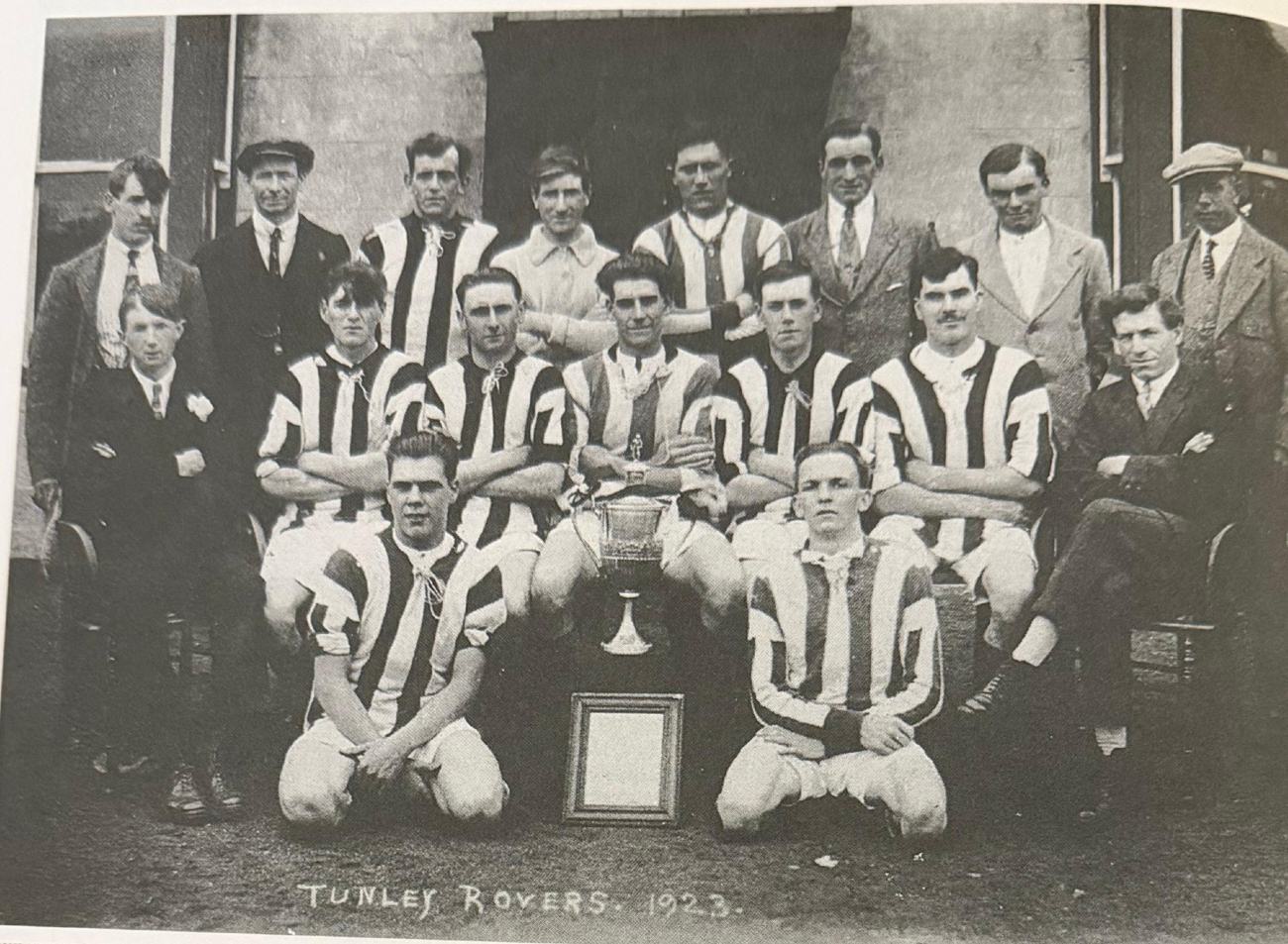 Tunley Rovers team in black and white striped shirts with a cup, labelled Tunley Rovers 1923