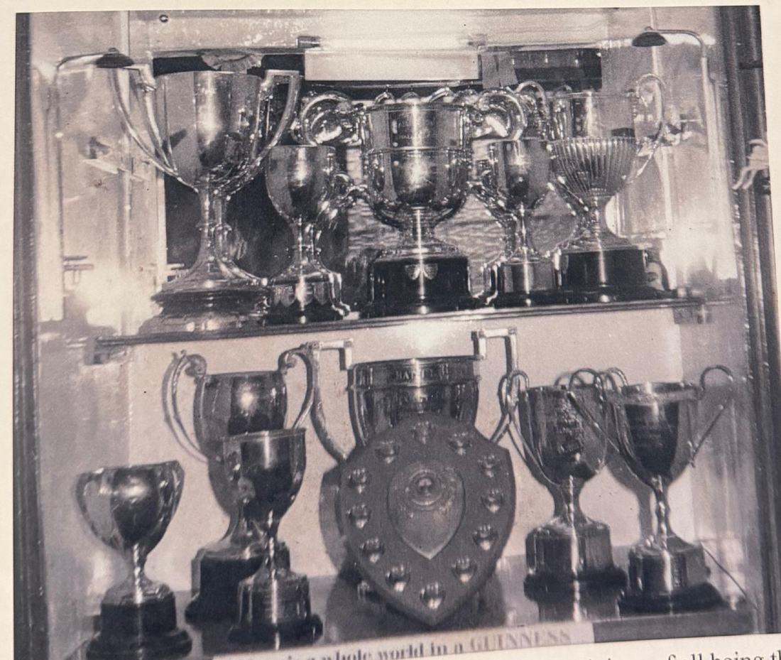 A glass cabinet holding twelve cups and a shield